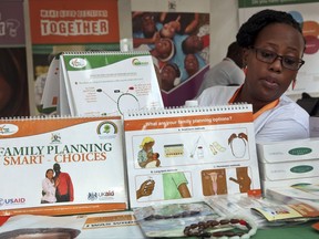 In this photo taken Tuesday, Sept. 26, 2017, health worker Sylvia Marettah Katende displays reproductive health products and information at a family planning exhibition in Kampala, Uganda. Over half of the world's population growth between now and 2050 will take place in Africa and Uganda, a leader in taking on global health issues like AIDS, is turning to "champion men" to promote vasectomies in family planning. (AP Photo/Stephen Wandera)