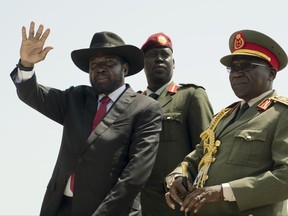 FILE - In this Thursday, July 9, 2015, file photo, South Sudan's President Salva Kiir, left, accompanied by then army chief of staff Paul Malong, right, waves during an independence day ceremony in the capital Juba, South Sudan. Tensions are high Saturday, Nov. 4, 2017, in Juba after President Salva Kiir sent troops to surround the home of former military chief of staff Paul Malong, disarm his bodyguards and remove all weapons. (AP Photo/Jason Patinkin, File)