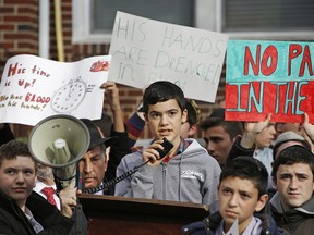 Student Avi Balsam, center, reads a politician's statement as he and other Orthodox Jewish high school students protest across the street from the house of former Nazi concentration camp guard Jakiw Palij, who worked as a guard at the Nazi German Trawniki camp in occupied Poland during World War II.