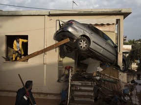 Workers work to remove a car from the entrance of a house in the town of Mandra, western Athens, on Thursday, Nov. 16, 2017. A major flash flood on Wednesday left at least 16 people dead, turned streets into torrents of mud and debris that swept away cars, collapsed walls and submerged parts of a major highway. (AP Photo/Petros Giannakouris)