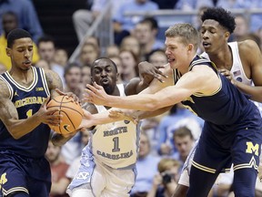 North Carolina's Theo Pinson (1) and Sterling Manley, right, reach for the ball with Michigan's Charles Matthews (1) and Moritz Wagner during the first half of an NCAA college basketball game in Chapel Hill, N.C., Wednesday, Nov. 29, 2017. (AP Photo/Gerry Broome)