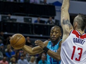 Charlotte Hornets guard Kemba Walker, left, passes around Washington Wizards center Marcin Gortat, of Poland, in the first half of an NBA basketball game in Charlotte, N.C., Wednesday, Nov. 22, 2017. (AP Photo/Nell Redmond)