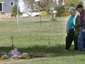 In this March 23, 2016 photo, a couple who identified themselves as the parents-in-law of Navy veteran Charles R. Ingram visit the memorial at the site where Ingram set himself ablaze outside the Veterans Affairs Outpatient Clinic in Northfield, N.J. Ingram went nearly a year without a mental health appointment or medication, one of several serious problems government investigators found with the clinic in a report released Thursday, Nov. 16, 2017. (Michael Ein/The Press of Atlantic City via AP)