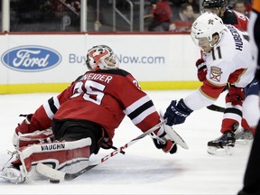 New Jersey Devils goalie Cory Schneider (35) blocks a shot by Florida Panthers left wing Jonathan Huberdeau (11) during the first period of an NHL hockey game, Saturday, Nov. 11, 2017, in Newark, N.J. (AP Photo/Julio Cortez)