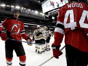 Boston Bruins players, center, celebrate a goal by center Patrice Bergeron (37) as New Jersey Devils' Brian Boyle, left, and Miles Wood, right, skate by during the first period of an NHL hockey game, Wednesday, Nov. 22, 2017, in Newark, N.J. (AP Photo/Julio Cortez)