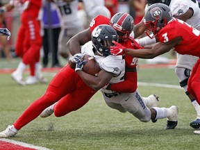 Utah State running back LaJuan Hunt, center, is tackled by New Mexico defensive lineman Kene Okonkwo (98) and cornerback D'Angelo Ross (3) 1 yard short of the end zone during the first half of an NCAA college football game in Albuquerque, N.M., Saturday, Nov. 4, 2017. Hunt scored a touchdown in the next down. (AP Photo/Andres Leighton)