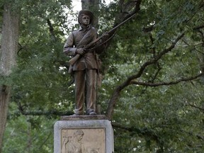 FILE - In this Aug. 22, 2017, file photo, police stand by a Confederate monument nicknamed "Silent Sam" at the University of North Carolina in Chapel Hill, N.C. The university's board heard from more than 30 speakers who oppose the campus Confederate monument, Wednesday, Nov. 15,  at a comment session during its bimonthly meeting. The statue of an anonymous rebel known as "Silent Sam" has been the site of demonstrations during a nationwide debate on Confederate monuments.  (AP Photo/Gerry Broome, File)