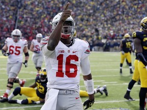 FILE - In this Nov. 28, 2015, file photo, Ohio State quarterback J.T. Barrett (16) points to the crowd after a touchdown during the second half of an NCAA college football game against Michigan, in Ann Arbor, Mich. Barrett has shattered nearly every Ohio State passing and scoring record but isn't considered a top NFL prospect. He helped win a national championship but has heard hysterical fans demand that he be benched. For all of his ups and downs through five years at Ohio State, Barrett  _ who plays his last regular-season game Saturday against Michigan _ is undeniably a winner. (AP Photo/Carlos Osorio, File)