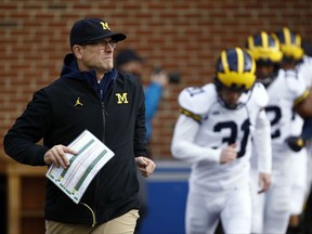FILE - In this Nov. 11, 2017, file photo, Michigan coach Jim Harbaugh runs onto the field with his team before an NCAA college football game against Maryland in College Park, Md. Harbaugh is winless against Ohio State in the three rivalry games since he became coach. (AP Photo/Patrick Semansky, File)