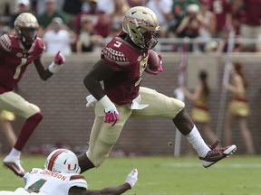 FILE - In this Oct. 7, 2017, file photo, Florida State's Jacques Patrick eludes Miami's Jaquan Johnson to gain yardage in the first quarter of an NCAA college football game,in Tallahassee, Fla.  Florida State's offense has been decimated by injuries, but the Seminoles are getting a rare bit of good news. Running back Jacques Patrick was feared lost for the season after an injury on Oct. 21 against Louisville but indications are he could be back when the Seminoles travel to No. 3 Clemson on Saturday. (AP Photo/Steve Cannon, File)