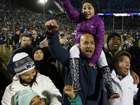 FILE - In this Nov. 26, 2016, file photo, Penn State head coach James Franklin, holding his younger daughter Addy Franklin, on his shoulders with his wife Fumi Franklin, left, holding their older daughter Shola Franklin, and athletic director Sandy Barbour, right, sing the school alma mater after defeating Michigan State 45-12 in an NCAA college football game in State College, Pa. No. 7 Penn State faces No. 24 Michigan State on Saturday. (AP Photo/Chris Knight, File)
