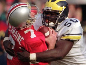 FILE - In this Nov. 23, 1996, file photo, Ohio State quarterback Joe Germaine, left, is sacked by Michigan defender James Hall, ending a drive during the third quarter of an NCAA college football game in Michigan's 13-9 upset victory over No. 2 Ohio State at Ohio Stadium in Columbus, Ohio. (AP Photo/Charles Rex Arbogast, File)