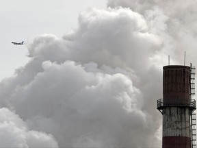 FILE - In this Feb. 28, 2017 file photo, a passenger airplane flies behind steam and white smoke emitted from a coal-fired power plant in Beijing. On Monday, Nov. 13, 2017, scientists projected that global carbon pollution has risen in 2017 after three straight years when the heat-trapping gas didn't go up at all. (AP Photo/Andy Wong, File)