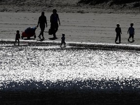 FILE - In this Tuesday, Jan. 25, 2011, file photo, visitors are silhouetted by the morning sun as they walk along the beach at Pillar Point in Half Moon Bay, Calif. Young parents are often torn between two savings goals: college for their kids and their own retirement. There are strategies that can help satisfy both goals. (AP Photo/Marcio Jose Sanchez, File)