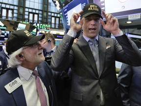 FILE - In this Wednesday, Nov. 1, 2017, file photo, trader Peter Tuchman, left, and New York Stock Exchange President Tom Farley don caps marking "Dow 23,500," on the trading floor as the index crosses the milestone. The stock market may have appeared to Donald Trump as "a big bubble" before he was elected, but he's had plenty of reasons to tout Wall Street's gains as president. In the year since Trump's election, the Standard & Poor's 500 index has notched at least 60 record highs and risen 21.1 percent. (AP Photo/Richard Drew, File)