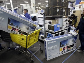 FILE - In this Thursday, Nov. 23, 2017, file photo, people wait to pay for televisions as they shop a sale at a Best Buy store on Thanksgiving Day, in Overland Park, Kan. For the five-day period that ended the Monday after Thanksgiving, shoppers seemed to spend more in 2017 compared to a year earlier. (AP Photo/Charlie Riedel, File)