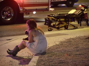 FILE - In this Oct. 2, 2017 file photo, a woman sits on a curb at the scene of a shooting outside of a music festival along the Las Vegas Strip, in Las Vegas. It came as little surprise to producers, but Showtime's documentary series this fall on mass shooting incidents was itself disrupted by mass shootings. The network cut back on reruns of the series following the Oct. 1 attack at a country music concert in Las Vegas that killed 58 people and injured hundreds. An episode that identified the 2016 Orlando nightclub shooting as the nation's most deadly event had to be changed because Las Vegas made that fact outdated.(AP Photo/John Locher, File)