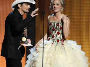 FILE - In this Nov. 10, 2010 file photo, co-host Brad Paisley, left, accepts the Entertainer of the Year Award as co-host Carrie Underwood looks on at the 44th Annual Country Music Awards in Nashville, Tenn. Paisley and Underwood are celebrating their 10-year anniversary as hosts of the Country Music Association Awards. The duo has hosted the show consecutively since 2008. They return Wednesday for the 2017 CMA Awards. (AP Photo/Mark Humphrey, File)