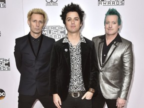 FILE - In this Nov. 20, 2016 file photo, Mike Dirnt, from left, Billie Joe Armstrong, and Tre Cool, of Green Day, arrive at the American Music Awards in Los Angeles. The band will release their latest, "Greatest Hits: God's Favorite Band," on Friday. (Photo by Jordan Strauss/Invision/AP)