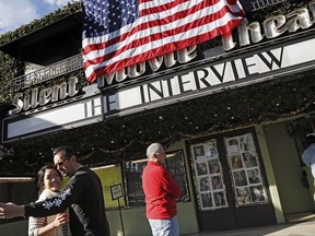 FILE - In this Dec. 25, 2014, file photo, a visitor takes a selfie with his friend in front of the Cinefamily at Silent Movie Theater in Los Angeles, prior to attending the movie "The Interview." The independent movie theater Cinefamily, which had numerous celebrity supporters, said Tuesday, Nov. 14, 2017, it is closing in the wake of investigations into the sexual misconduct of two of its executives. (AP Photo/Richard Vogel, File)
