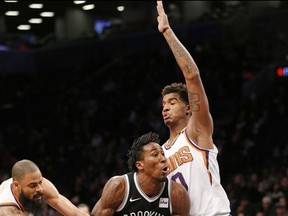 Phoenix Suns center Tyson Chandler, left, and Phoenix Suns forward Marquese Chriss (0) gang up on Brooklyn Nets forward Rondae Hollis-Jefferson (24) in the first half of an NBA basketball game, Tuesday, Oct. 31, 2017, in New York. (AP Photo/Kathy Willens)
