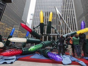 In this Saturday, Nov. 18, 2017, photo employees of the American Christmas company set up the Christmas display in front of 1221 Avenue of the Americas in Midtown Manhattan. American Christmas in suburban Mount Vernon is essentially a decorations attic for the nation's largest city and the surrounding area. (AP Photo/Mary Altaffer)