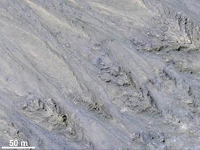 This image provided by NASA shows the inner slope of a Martian crater which has several of the seasonal dark streaks called "recurrent slope lineae," or RSL, that a November 2017 report interprets as granular flows, rather than darkening due to flowing water. Arizona scientists said Monday, Nov. 20, 2017 that these lines appear more like dry, steep flows of sand, rather than water trickling downhill, at or near the surface. (NASA via AP)