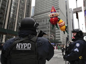FILE - In this Nov. 24, 2016, file photo, New York Police counterterrorism personnel watch as the Macy's Thanksgiving Day parade makes its way down Sixth Avenue in New York. After the deadly truck attack in Manhattan on Oct. 31, 2017, every intersection along the 2 1/2-mile parade route that stretches from Central Park to the Macy's flagship store on 34th Street will be blocked to traffic. (AP Photo/Julie Jacobson, File)