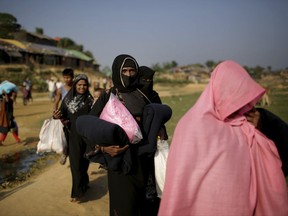 FILE - In this Tuesday, Nov. 21, 2017, file photo, Rohingya Muslim women carry blankets and other supplies they collected from aid distribution centers in Kutupalong refugee camp in Bangladesh. The United States declared the ongoing violence against Rohingya Muslims in Myanmar to be "ethnic cleansing" on Wednesday, Nov. 22, putting more pressure on the country's military to halt a brutal crackdown that has sent more than 600,000 refugees flooding over the border to Bangladesh. (AP Photo/Wong Maye-E, File)