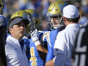 This photo taken Oct. 21, 2017, shows UCLA offensive coordinator Jedd Fisch, left, talking with quarterback Josh Rosen, center, and head coach Jim Mora during the second half of an NCAA college football game against Oregon in Pasadena, Calif.  Fisch is UCLA's head coach for the week after Jim Mora's surprise firing, and he's hoping to extend that gig for at least another month. The veteran offensive coordinator has been promoted for the Bruins' season finale against California, and Fisch hopes to honor Mora's legacy with a win that would make UCLA bowl-eligible. (AP Photo/Mark J. Terrill)