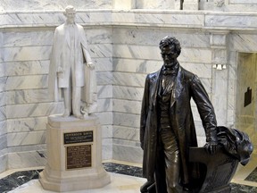 FILE - In a Wednesday, Aug. 5, 2015 file photo, a statue of Jefferson Davis, left, overlooks the statue of Abraham Lincoln in the Rotunda of the Kentucky State Capitol in Frankfort Ky. A plaque attached to the 15-foot-tall (4.5 meters) marble statue of Davis, declaring Jefferson Davis to be a hero and a patriot will not be removed until a lawyer with Gov. Matt Bevin's administration can determine whether the commission that voted to get rid of the marker has the authority to do it.   (AP Photo/Timothy D. Easley, File)