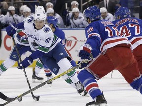 Vancouver Canucks' Markus Granlund, left, moves the puck around New York Rangers defenders during the first period of an NHL hockey game, Sunday, Nov. 26, 2017, in New York. (AP Photo/Seth Wenig)