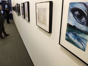 People look at an exhibit of artwork by detainees at the Guantanamo Bay Detention Camp, at the John Jay College of Criminal Justice in New York, Monday, Nov. 27, 2017. The artists, current and former terror suspects at the notorious Guantanamo Bay detention center, drew protest and prompted the Pentagon to bar the further release of works created at the military-run prison.  (AP Photo/Seth Wenig)