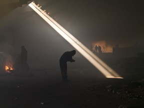 2017 AP YEAR END PHOTOS - A group of migrants, left, gather around a fire to warm themselves in an abandoned warehouse in Belgrade, Serbia, on Jan. 30, 2017. Hundreds of migrants have been sleeping in freezing conditions in central Belgrade looking for ways to cross the heavily guarded EU borders. (AP Photo/Muhammed Muheisen)