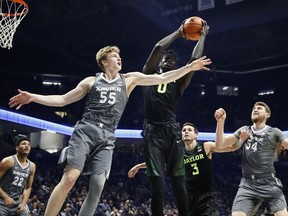 Baylor's Jo Lual-Acuil Jr. (0) rebounds against Xavier's J.P. Macura (55) in the first half of an NCAA college basketball game, Tuesday, Nov. 28, 2017, in Cincinnati. (AP Photo/John Minchillo)