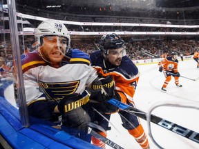 Magnus Paajarvi, left, of the St. Louis Blues, is rammed into the boards by Edmonton Oilers defenceman Kris Russell during NHL action Thursday night at Rogers Place in Edmonton. The Blues were 4-1 winners.