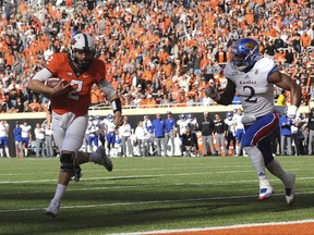 Kansas defensive end Dorance Armstrong Jr., right, chases after Oklahoma State quarterback Mason Rudolph as he scores a touchdown in the first half of an NCAA college football game between Kansas and Oklahoma St in Stillwater, Okla., Saturday, Nov. 25, 2017. (AP Photo/Brody Schmidt)