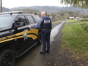 Oregon State Police senior trooper Mark Moore regulates traffic on Whispering Pines Way near Lookingglass, Wednesday Nov. 8, 2017 in Lookingglass, Ore. Authorities arrested a 16-year-old boy accused of fatally shooting three people in southwest Oregon. (Michael Sullivan/The News-Review via AP)