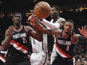 Portland Trail Blazers forward Noah Vonleh, left, Brooklyn Nets guard Spencer Dinwiddie, center and Portland Trail Blazers guard Damian Lillard, right, battle for a rebound under the basket during the first quarter of an NBA basketball game in Portland, Ore., Friday, Nov. 10, 2017. (AP Photo/Steve Dykes)