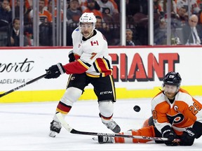 Calgary Flames' TJ Brodie, left, hits the puck just past Philadelphia Flyers' Claude Giroux, right, during the first period of an NHL hockey game, Saturday, Nov. 18, 2017, in Philadelphia. (AP Photo/Chris Szagola)
