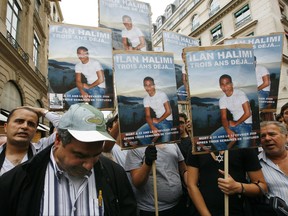 FILE - In this July 13 2009 file photo, memonstrators hold photographs of Ilan Halimi at the end of the two-month trial of a Paris gang who kidnapped, tortured and killed Halimi, a young French Jew in 2006. France's interior minister Gerard Collomb has condemned Thursday Nov. 2 2017 the desecration of a prominent Jewish grave plaque near Paris by unknown vandals as "cowardly and odious." The plaque in homage to Halimi, was pulled off, thrown on the ground and covered with anti-Semitic writing. (AP Photo/Jacques Brinon, File)
