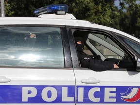 FILE - In this photo taken on June 6 2017, hooded police officers sit in a police car after a man attacked police officers patrolling in front of Notre Dame Cathedral, in Paris. Ten people suspected of using encrypted social networks to prepare a possible attack were arrested Tuesday in counterterrorism operations in France and Switzerland, according to French officials. (AP Photo/Christophe Ena, File)