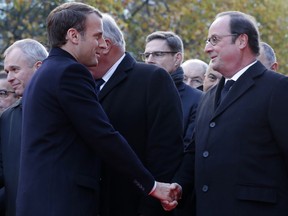 French President Emmanuel Macron, left, shakes hands with former French President Francois Hollande as they stand in front of a commemorative plaque outside the Stade de France stadium, in Saint-Denis, near Paris, Monday, Nov. 13, 2017. French President Emmanuel Macron, Paris Mayor Anne Hidalgo and victims' families are paying homage to 130 people killed two years ago when Islamic State extremists attacked the City of Light. (Philippe Wojazer, Pool via AP)