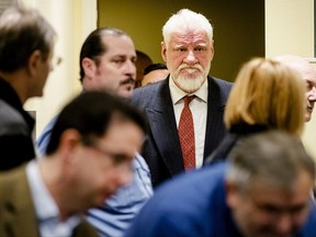 Slobodan Praljak, center, enters the Yugoslav War Crimes Tribunal in The Hague, Netherlands, Wednesday, Nov. 29, 2017, to hear the verdict in the appeals case. A United Nations war crimes tribunal is handing down its last judgment, in an appeal by six Bosnian Croat political and military leaders who were convicted in 2013 of persecuting, expelling and murdering Muslims during Bosnia's war. Wednesday's hearing is the final case to be completed at the groundbreaking International Criminal Tribunal for the former Yugoslavia before it closes its doors next month. (Robin van Lonkhuijsen,Pool Photo via AP)