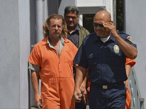 In this Oct. 4, 2016, file photo provided by the Samoa News, Dean Jay Fletcher, left, is escorted by a police officer after his initial appearance in the District Court of American Samoa in Pago Pago, American Samoa.