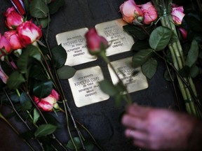 Roses are laid on four "Stolpersteine" (stumbling blocks) for Karolina Cohn and her family in Frankfurt, Germany, Monday, Nov. 13, 2017. Relatives participated  in a memorial ceremony for Karolina Cohn, a Jewish girl from Frankfurt who perished in the Holocaust more than 70 years ago. The story of her life and death had been all but erased by the Nazis, until archeologists last year unearthed a silver pendant engraved with her birthdate and birthplace at the grounds of the former Sobibor death camp.  (AP Photo/Michael Probst)