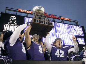 Western Mustangs' Andrew Thurston (42) and Myles Manalo (9) hold up the Vanier Cup as they celebrate with teammates after defeating the Laval Rouge et Or in Hamilton, Ont., on Saturday, November 25, 2017. THE CANADIAN PRESS/Peter Power