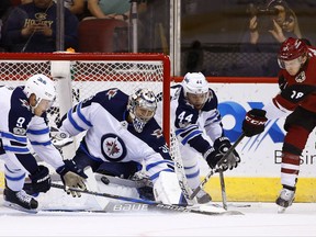 Arizona Coyotes center Christian Dvorak (18) gets his shot stopped by Winnipeg Jets center Andrew Copp (9), goalie Steve Mason (35) and defenseman Josh Morrissey (44) during the first period of an NHL hockey game Saturday, Nov. 11, 2017, in Glendale, Ariz. (AP Photo/Ross D. Franklin)