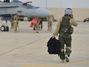 A Royal Canadian Armed Forces CF-18 Hornet fighter jet pilot from 4 Wing Cold Lake, Alberta walks down the flight line in Kuwait after his first combat mission over Iraq in support of Operation IMPACT on October 30, 2014.