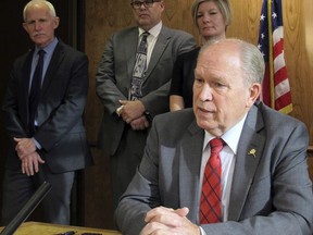 Alaska Gov. Bill Walker speaks, as members of his administration look on, after signing an administrative order creating a team charged with making recommendations to address climate change on Tuesday, Oct. 31, 2017, in Juneau, Alaska. The team will include up to 15 public members yet to be appointed. (AP Photo/Becky Bohrer)